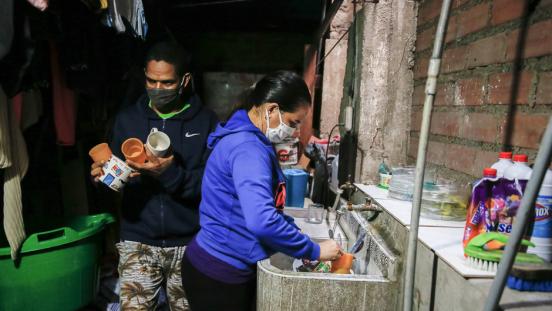 Venezuelan migrants washing dishes to keep house clean to prevent COVID-19.
